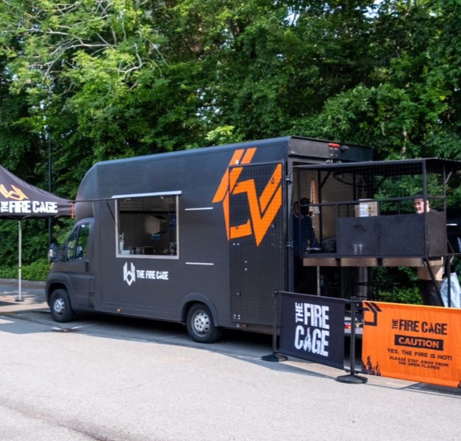 fire cage food truck parked in front of trees