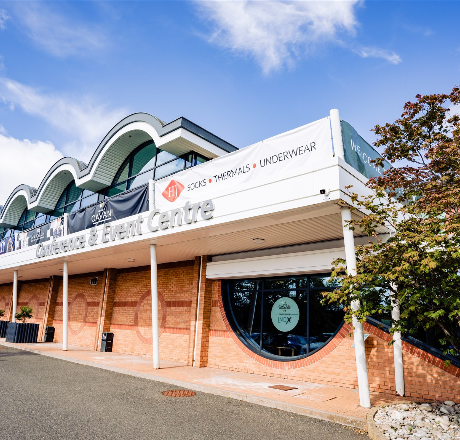 A modern event center with a curved roof design, featuring large windows and a banner that reads 