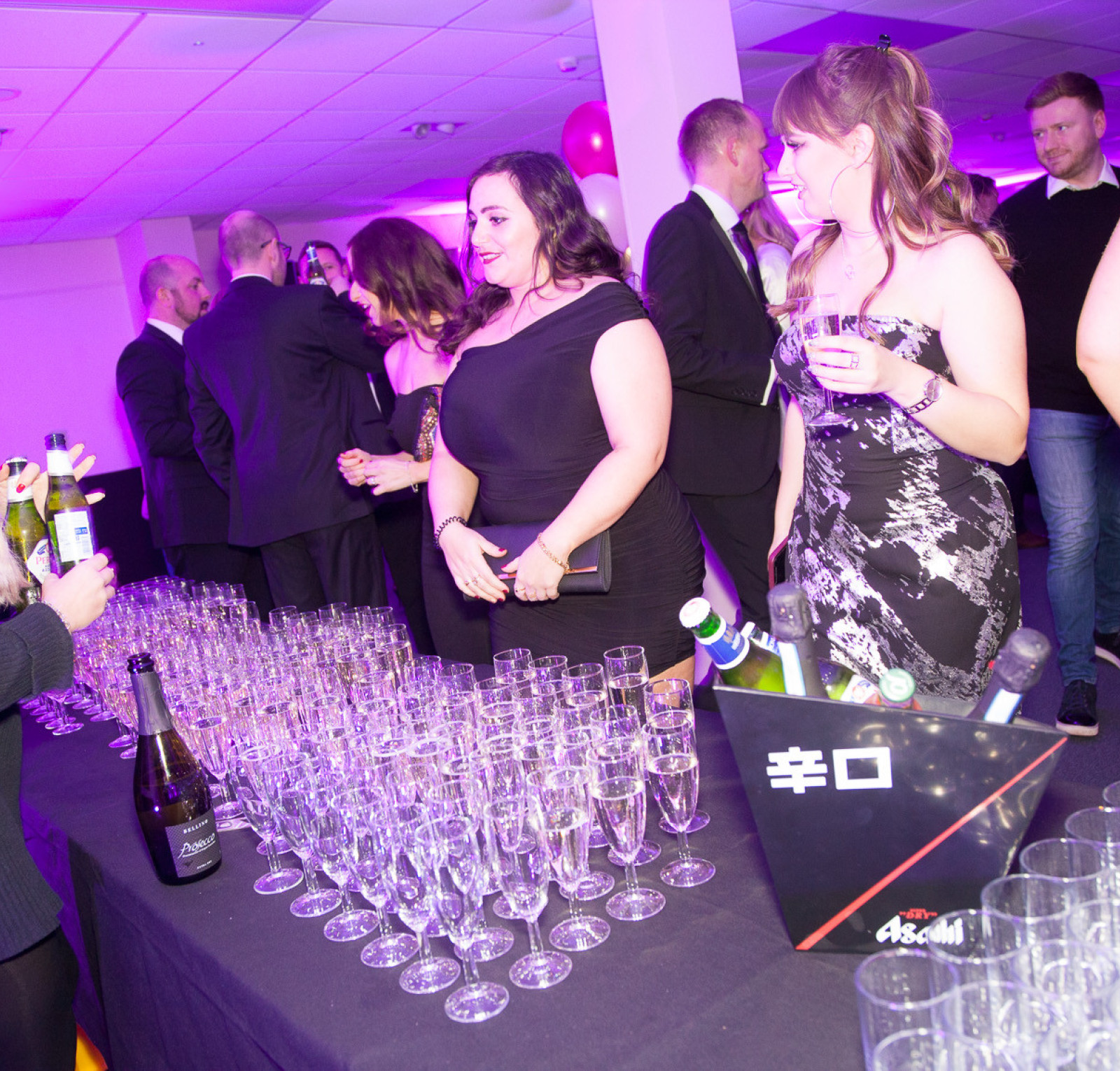 group of people stood in front of a long table filled with campagne glasses