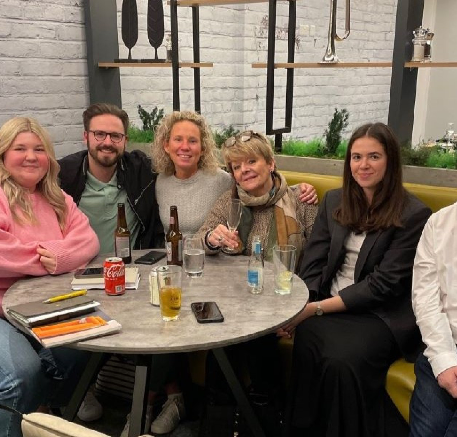 group of people sat around a table smiling at the camera