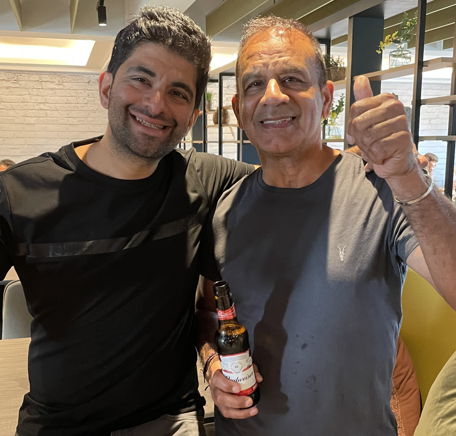 two men with beers in hand smailing at the camera