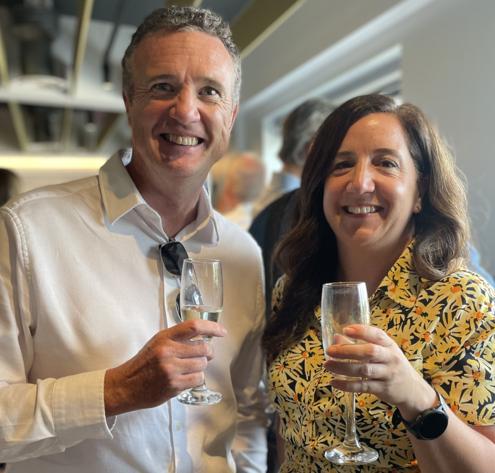 two people with champagne glasses, smiling at the camera