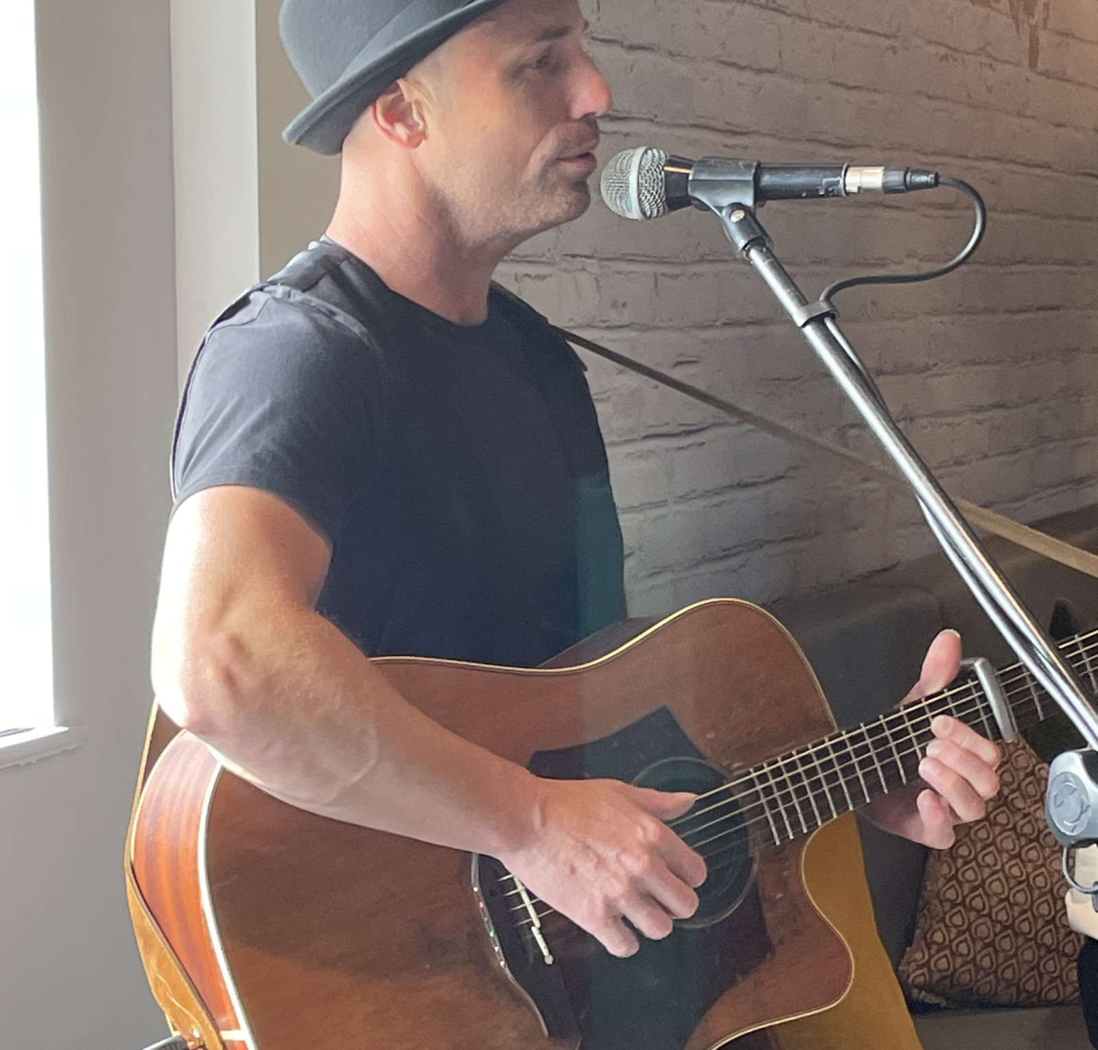 man playing guitar and signing into microphone