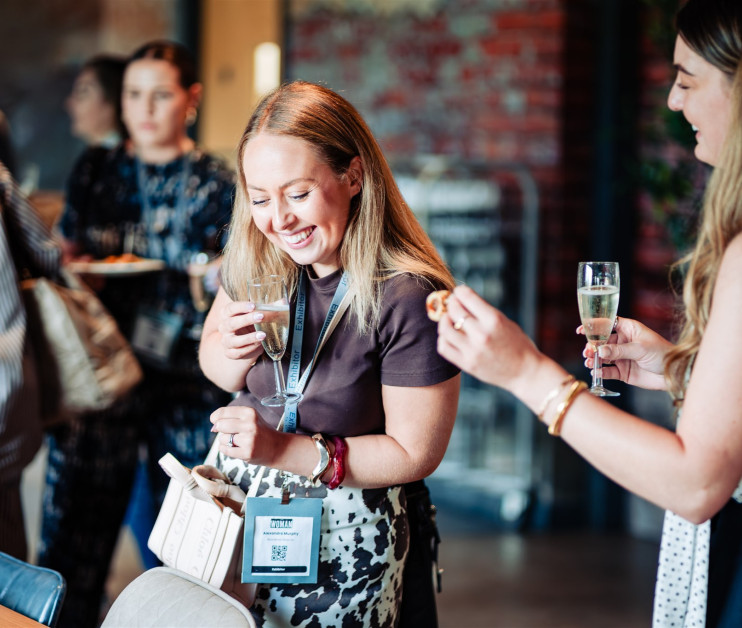two women laughing at a drinks reception