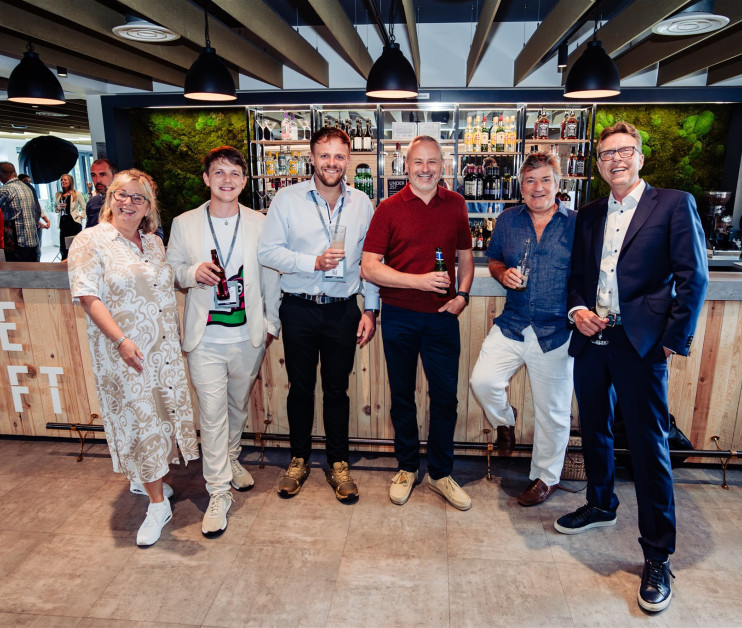 a group of six people standing in front of a bar, smiling at the camera