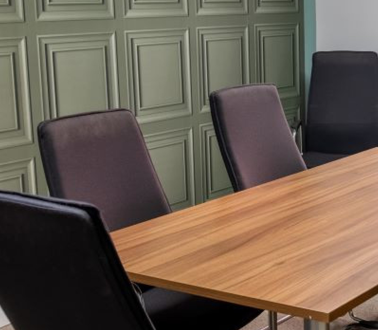 A spacious dining area featuring multiple wooden tables and chairs in various styles. The room is well-lit, with large windows and plants adding greenery. A buffet area is visible in the background, and modern decor enhances the ambiance.