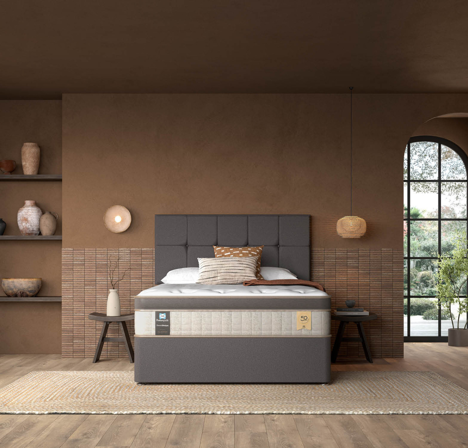 A stylish bedroom featuring a modern bed with a gray upholstered headboard. The bed is dressed in neutral bedding, complemented by decorative pillows. Surrounding the room are earthy tones, with shelves displaying vases and art pieces. A large window lets in natural light, revealing greenery outside. A woven rug adds texture to the wooden floor.