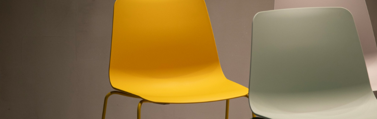 A bright yellow chair and a soft green chair are placed side by side against a neutral background.
