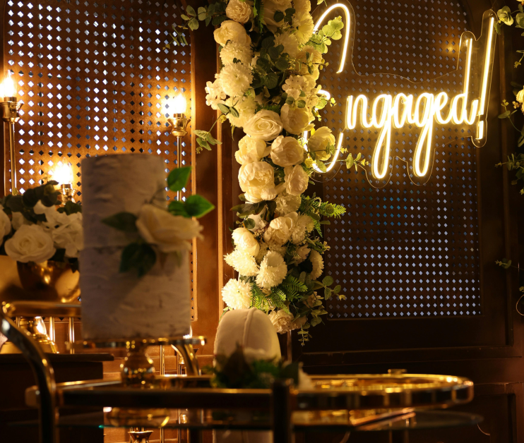 A beautifully decorated engagement setup featuring a glowing neon sign that reads 