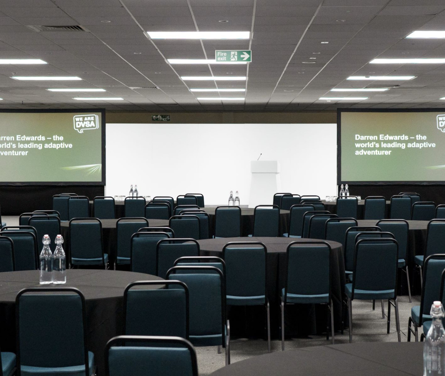 empty conference room set up with tables and chairs and two large screens