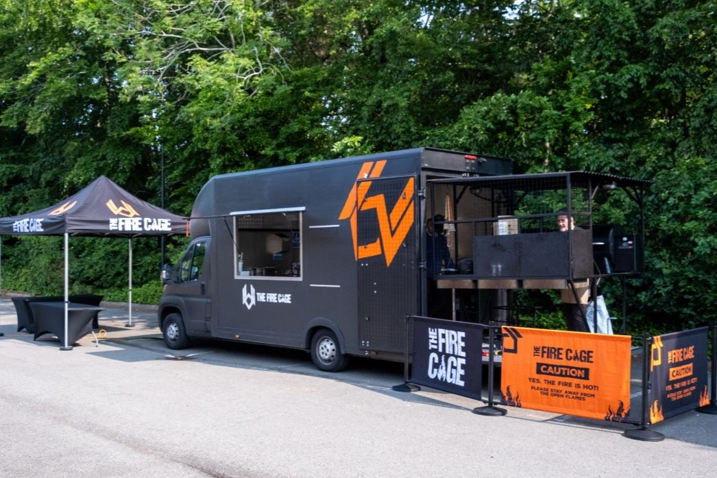 fire cage food truck parked in front of trees