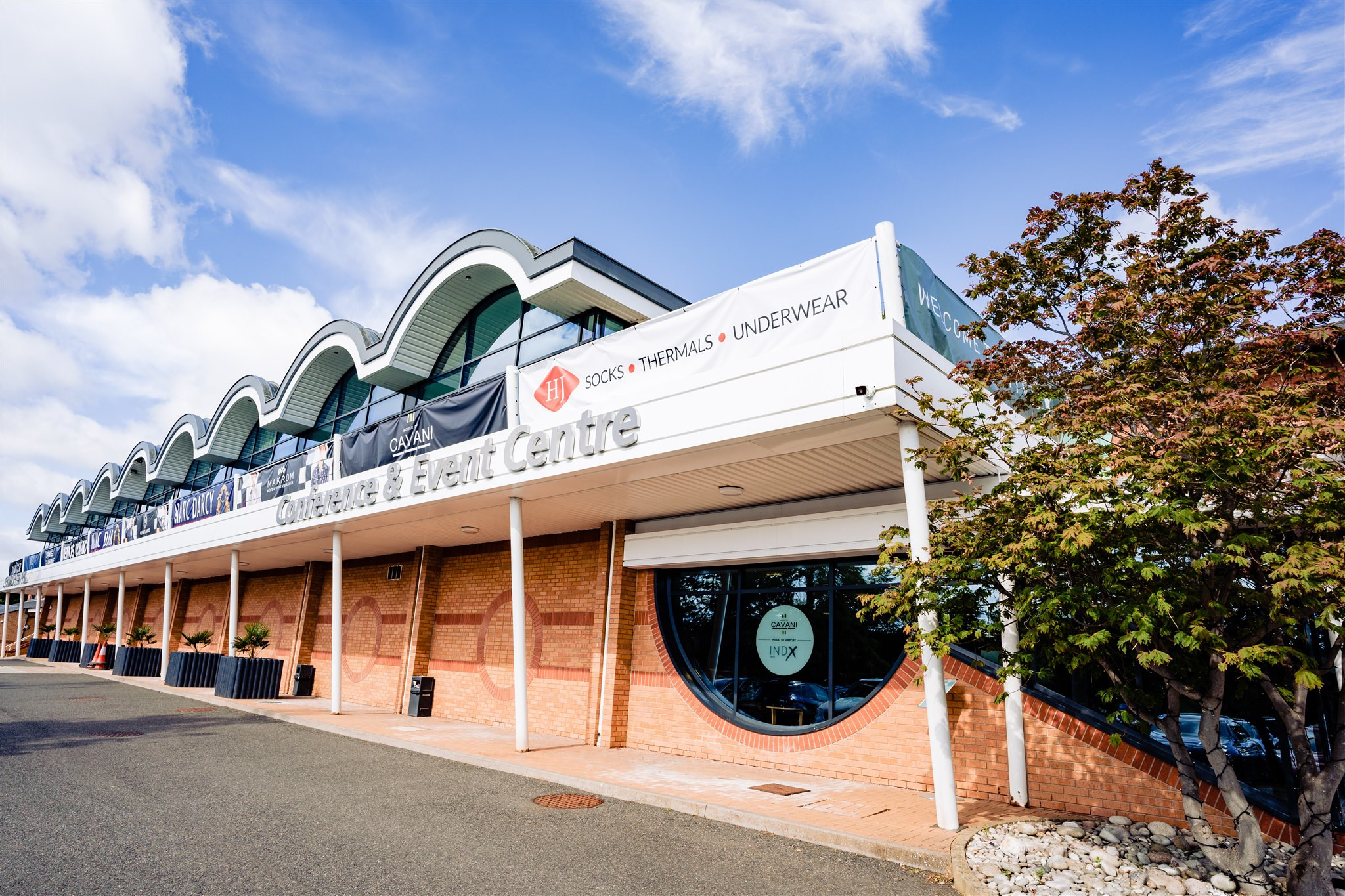 A modern event center with a curved roof design, featuring large windows and a banner that reads 