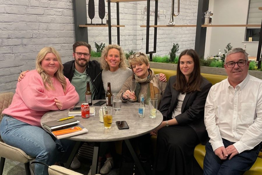 group of people sat around a table smiling at the camera