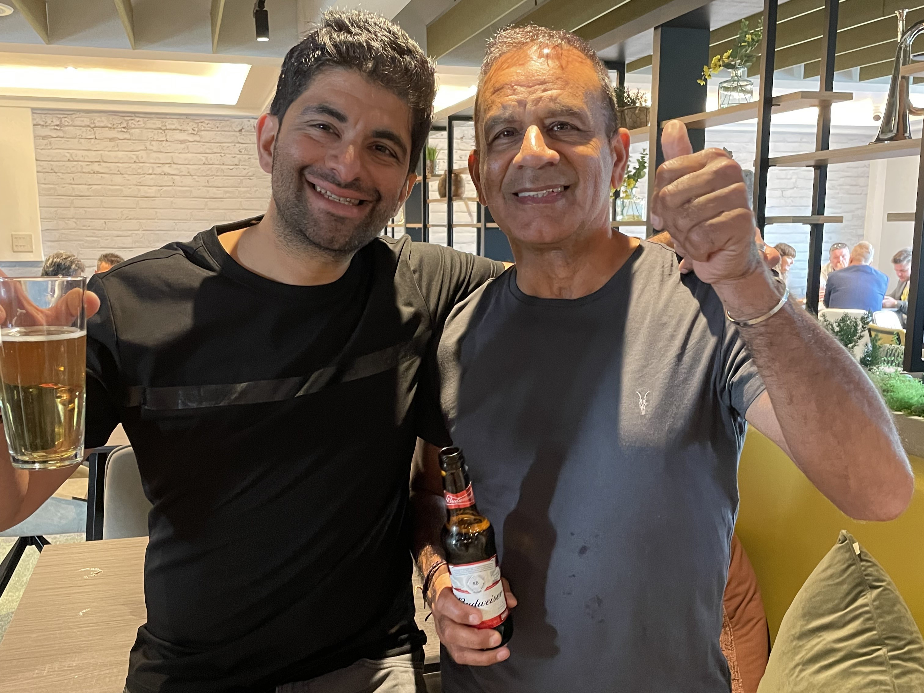 two men with beers in hand smailing at the camera