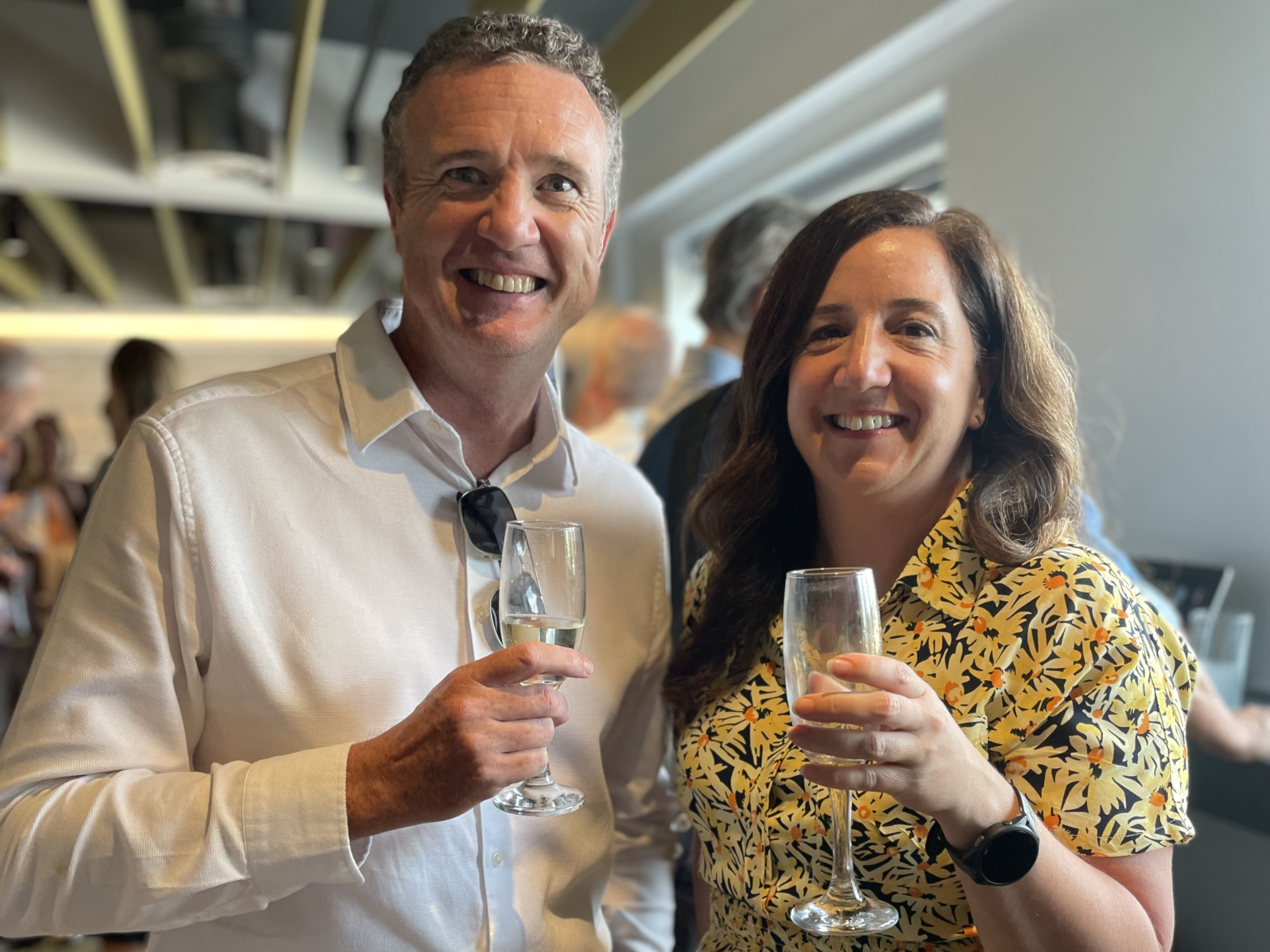 two people with champagne glasses, smiling at the camera