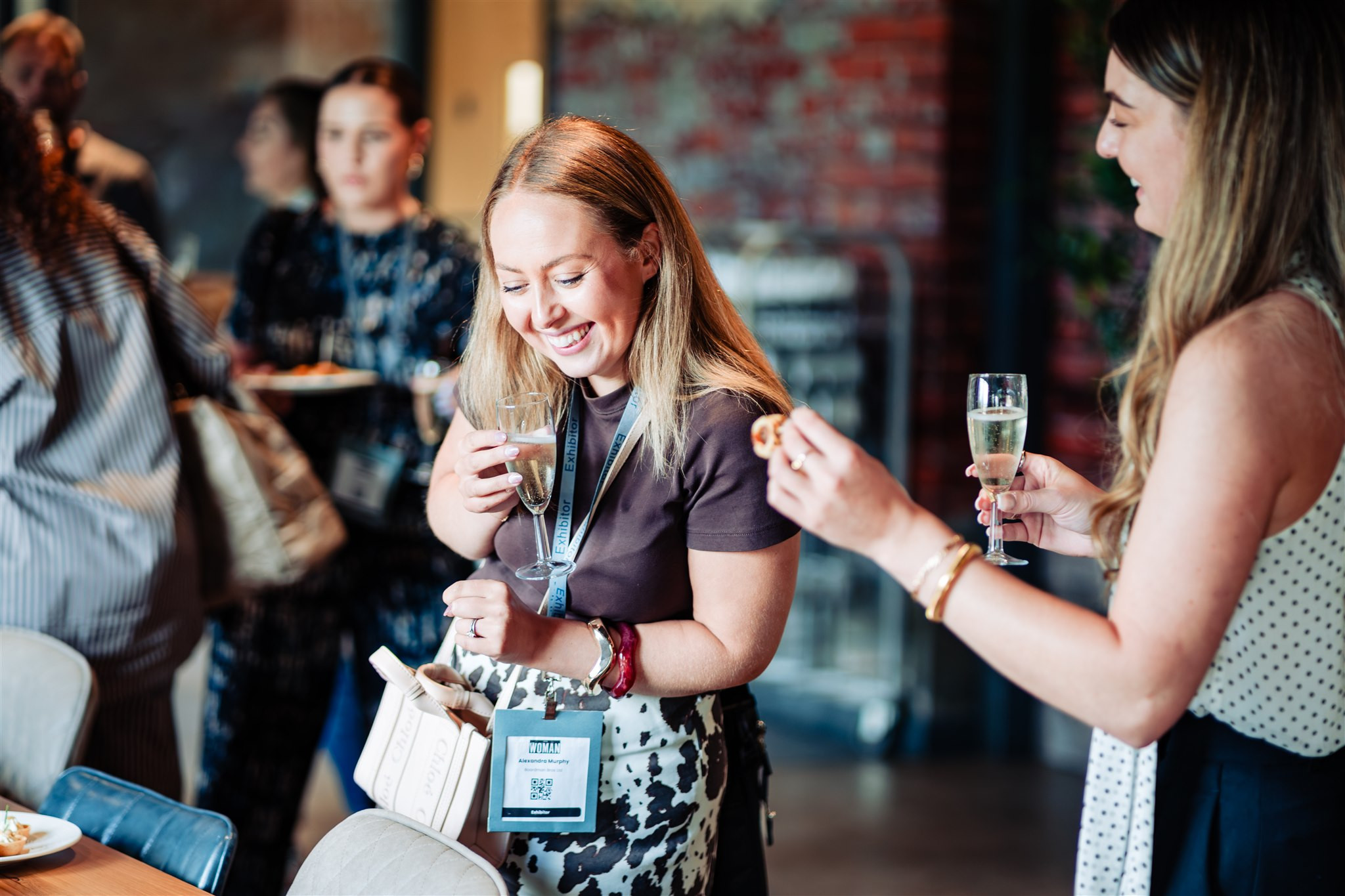two women laughing at a drinks reception